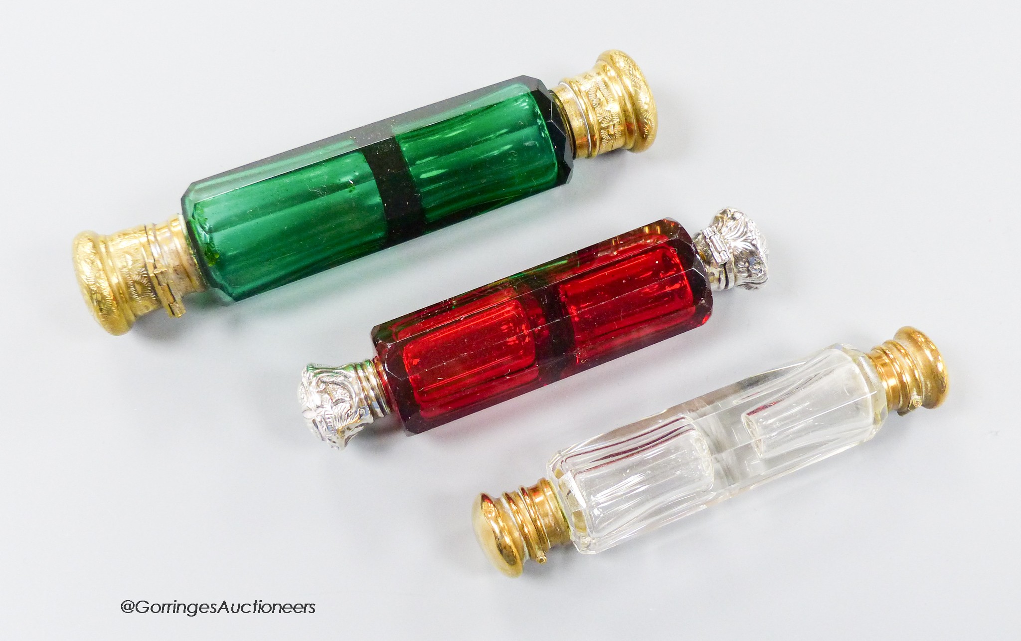 A late 19th century white metal mounted ruby glass decagonal double ended scent bottle, 12cm and two other base metal mounted glass scent bottles.